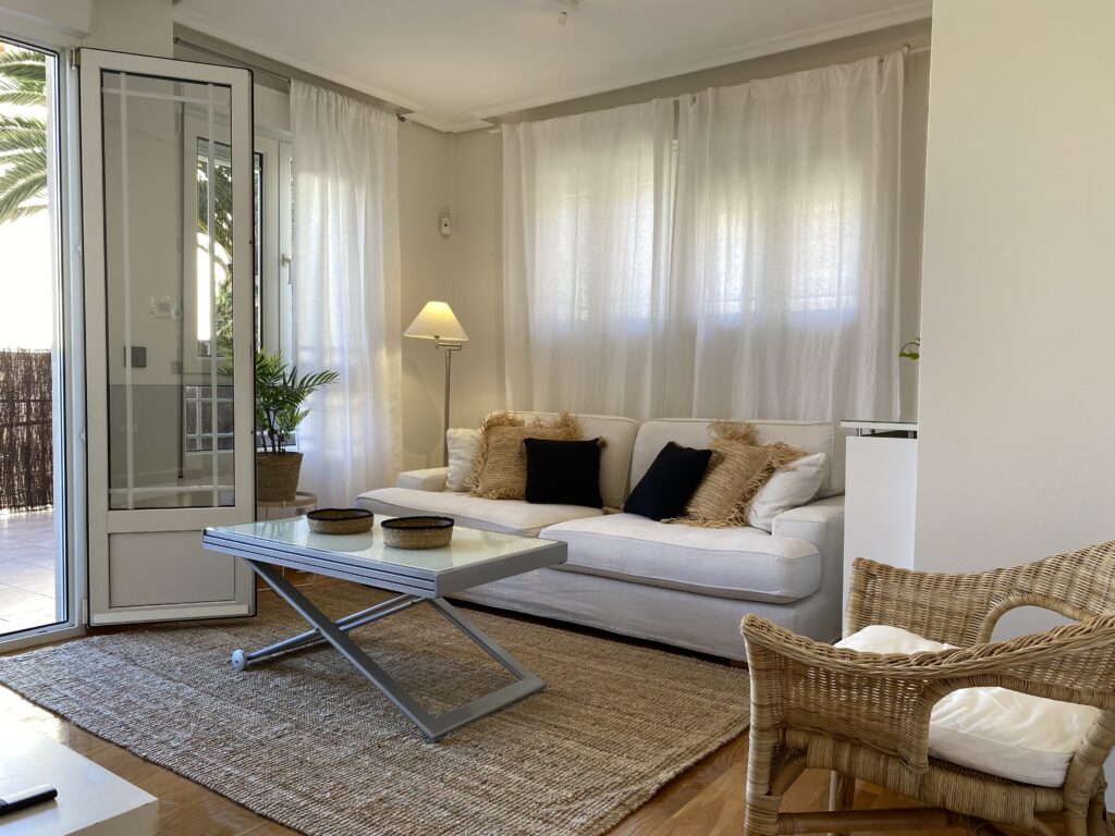 Salón con sofá blanco, mesa de centro y acceso a la terraza
