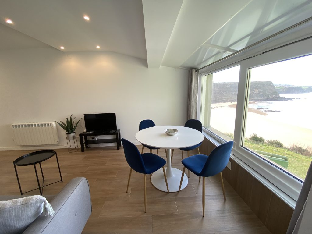 Salón con mesa de comedor, sofá y ventanal con vistas al mar