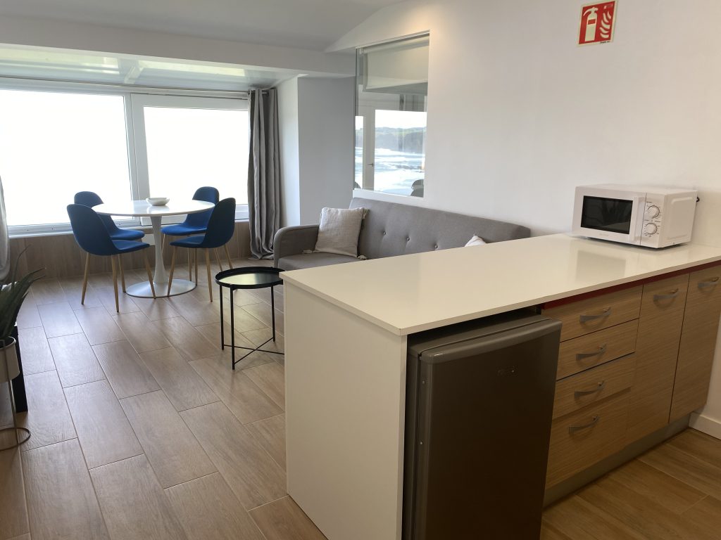 Cocina americana con barra blanca, microondas y muebles en madera clara