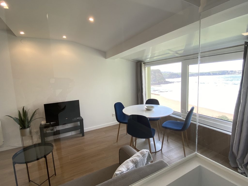 Salón con vistas al mar, mesa de comedor y televisión