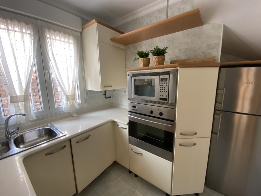 Cocina moderna con armarios crema, horno y microondas de acero.