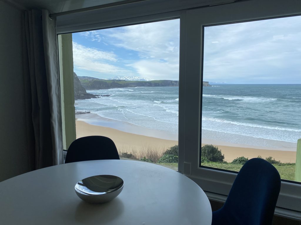 Mesa de comedor junto al ventanal con vistas a la playa y el mar