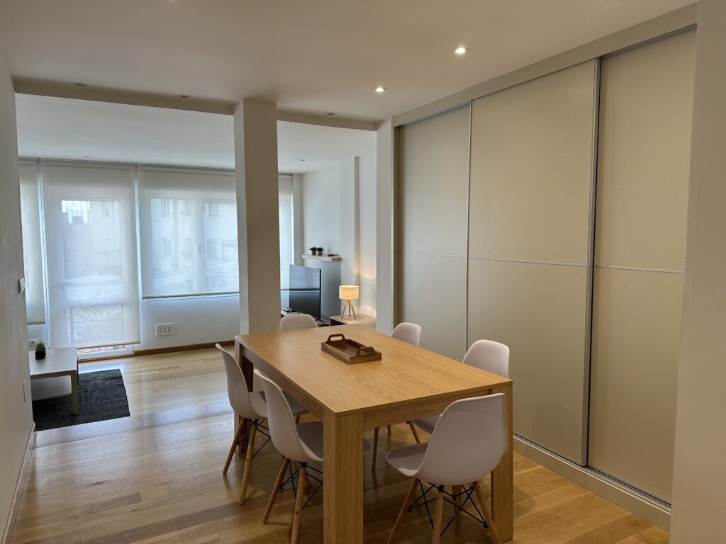 Comedor moderno con mesa de madera y sillas blancas.