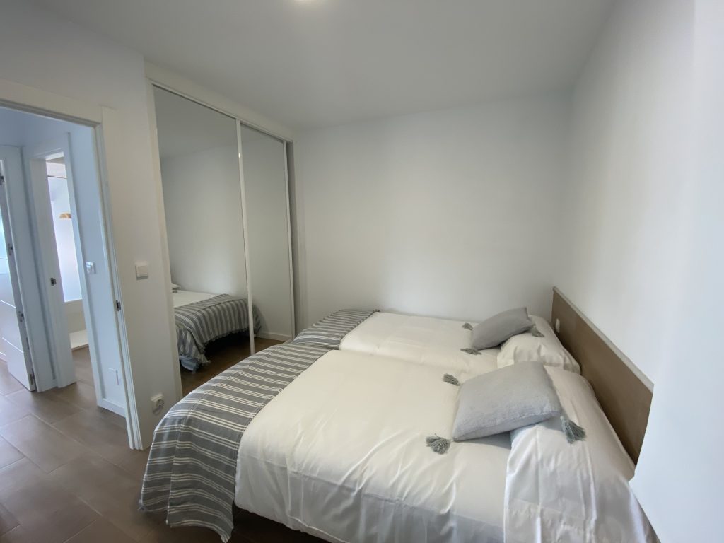 Dormitorio con cama doble, cojines a rayas y armario empotrado