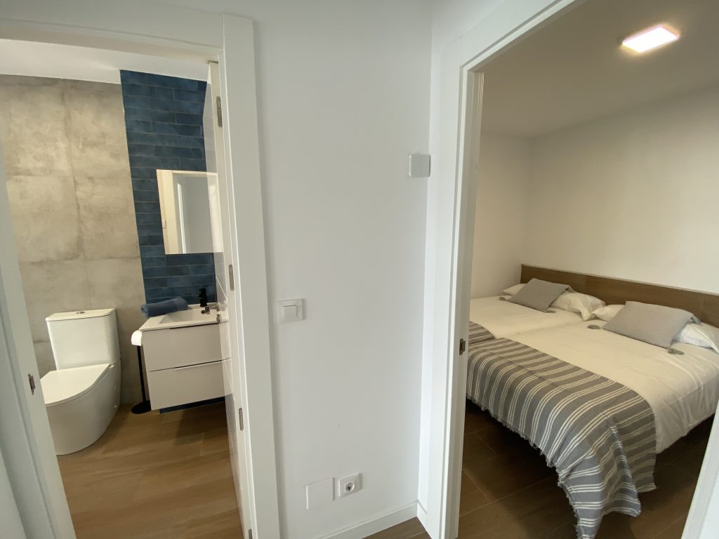 Acceso a baño con lavabo y dormitorio con cama doble