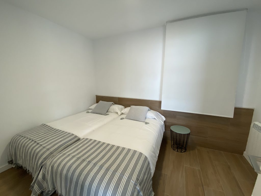 Dormitorio con dos camas individuales juntas y persiana enrollable