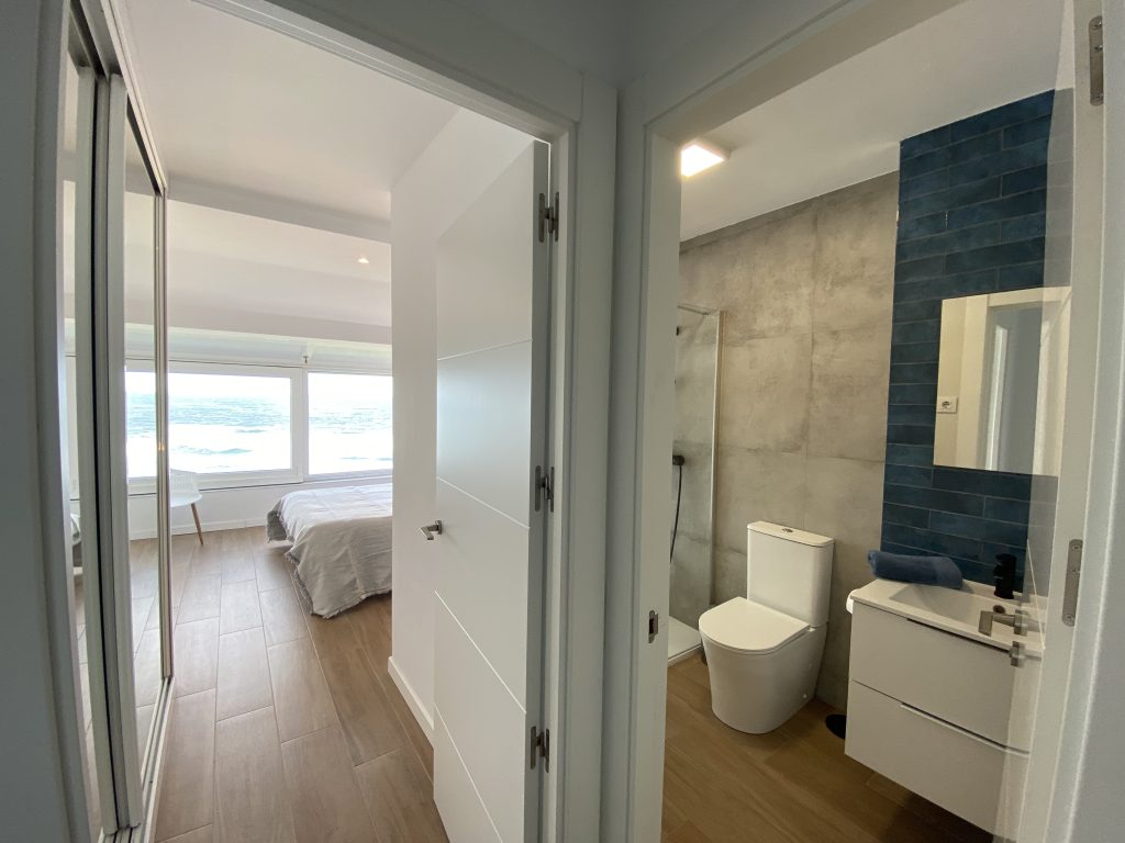 Pasillo con acceso a dormitorio con vistas al mar y a baño con ducha