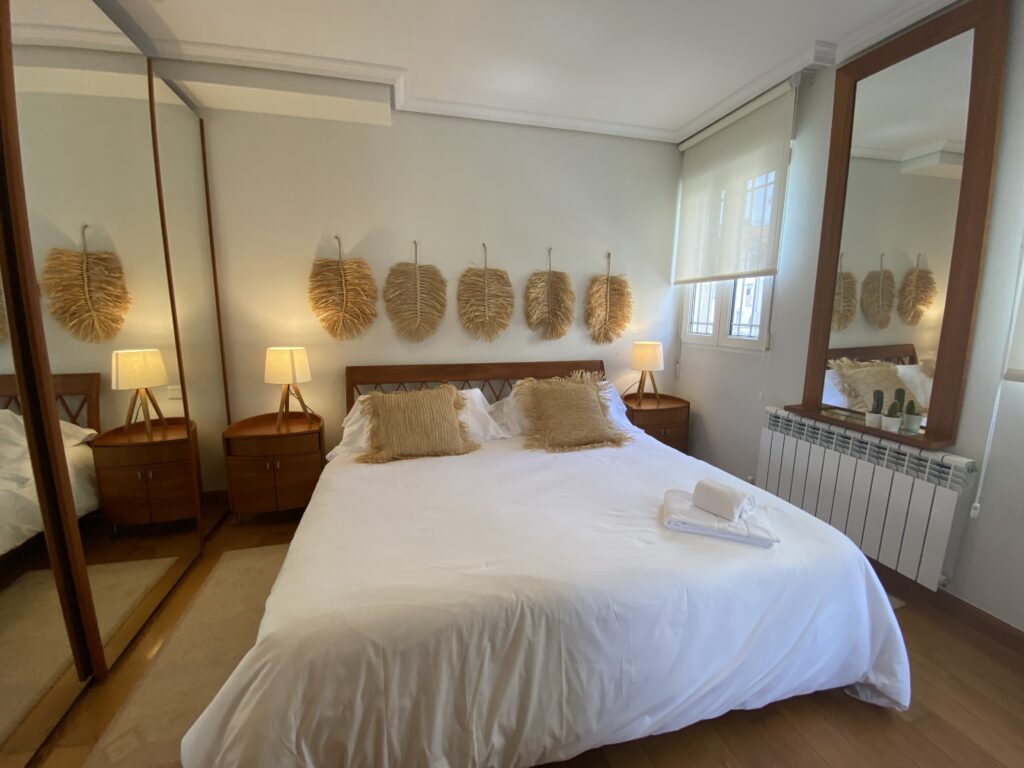 Dormitorio acogedor con cama blanca y decoración de hojas de fibra.