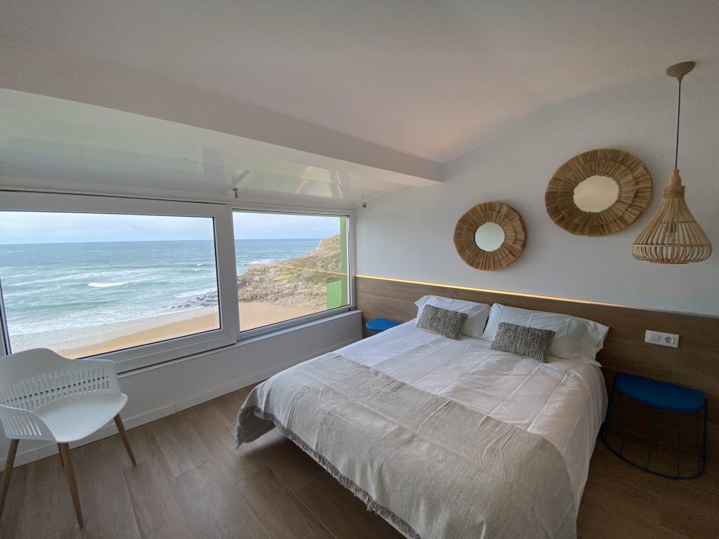 Dormitorio con cama doble, vistas al mar y decoración en tonos naturales