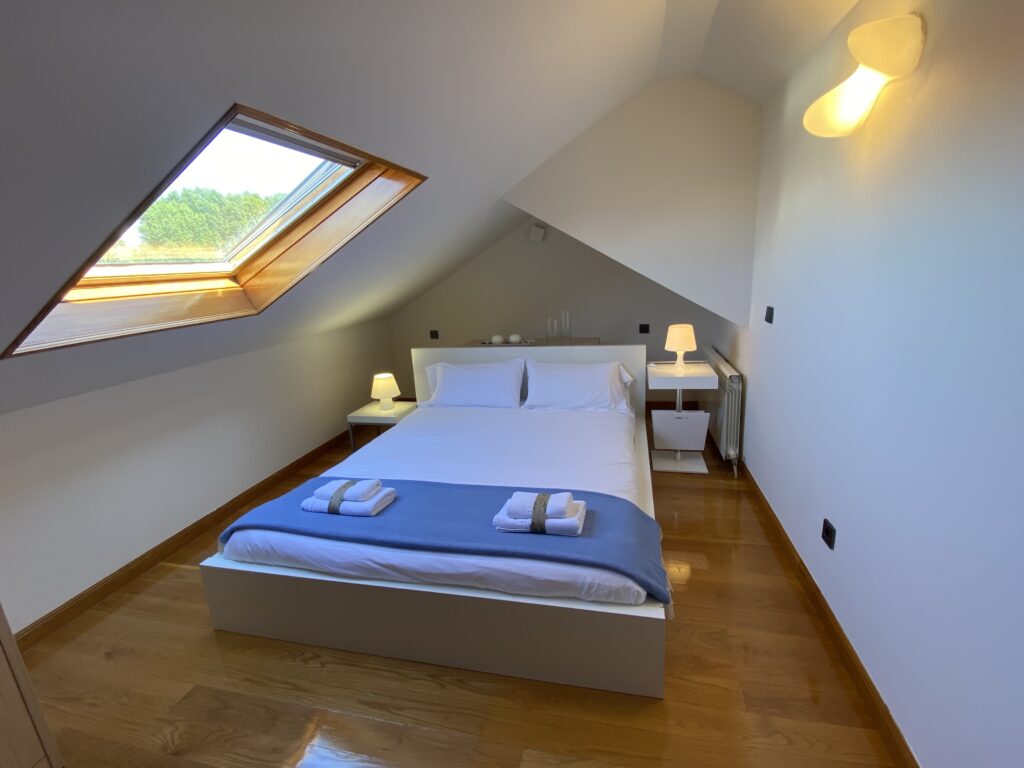 Dormitorio abuhardillado con cama doble y ventana de tejado