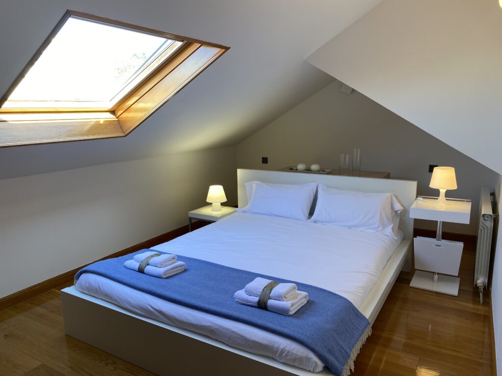Dormitorio abuhardillado con cama doble y ventana de tejado