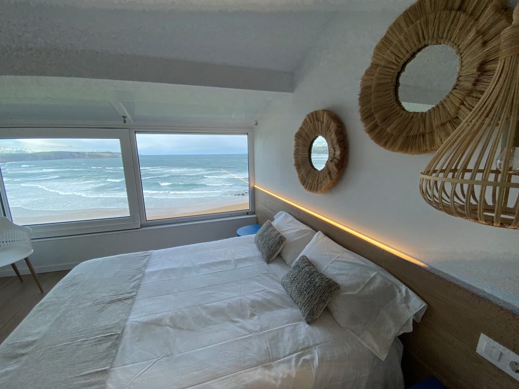 Dormitorio con cama doble, vistas frontales al mar y espejo decorativo