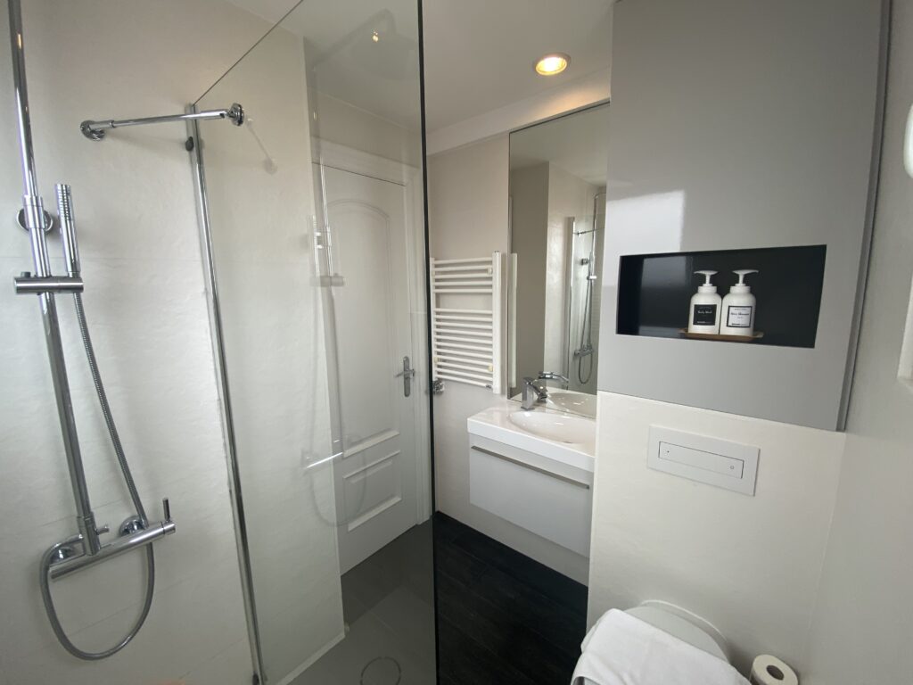 Baño con ducha de obra, mampara de cristal y mueble lavabo