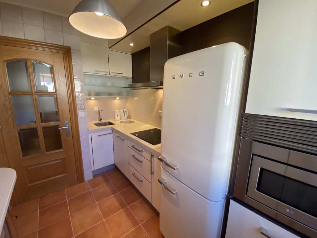 Cocina con frigorífico vintage blanco, vitrocerámica y muebles en blanco
